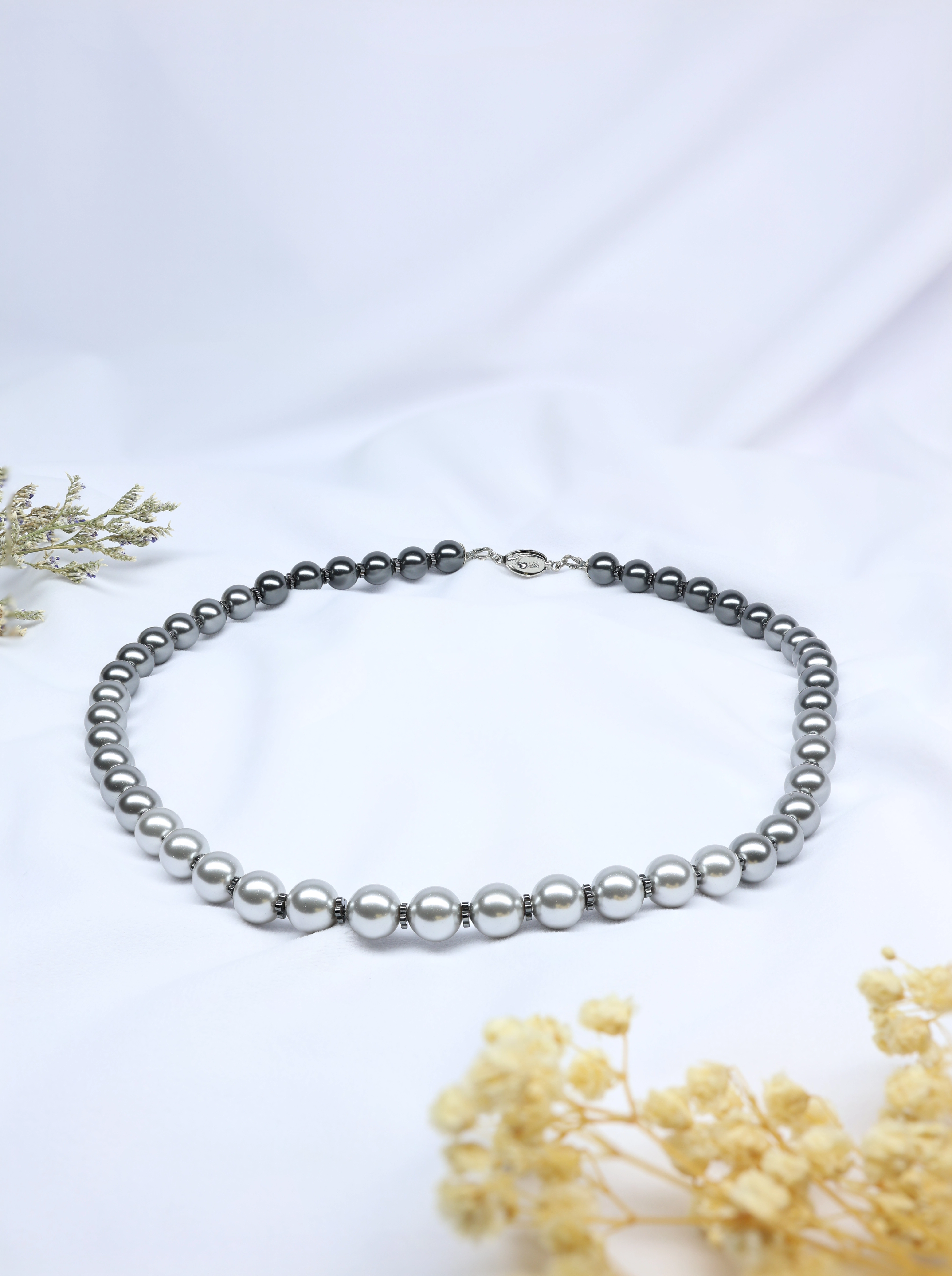 Black gradient Pearl necklace on a white background with dried flowers