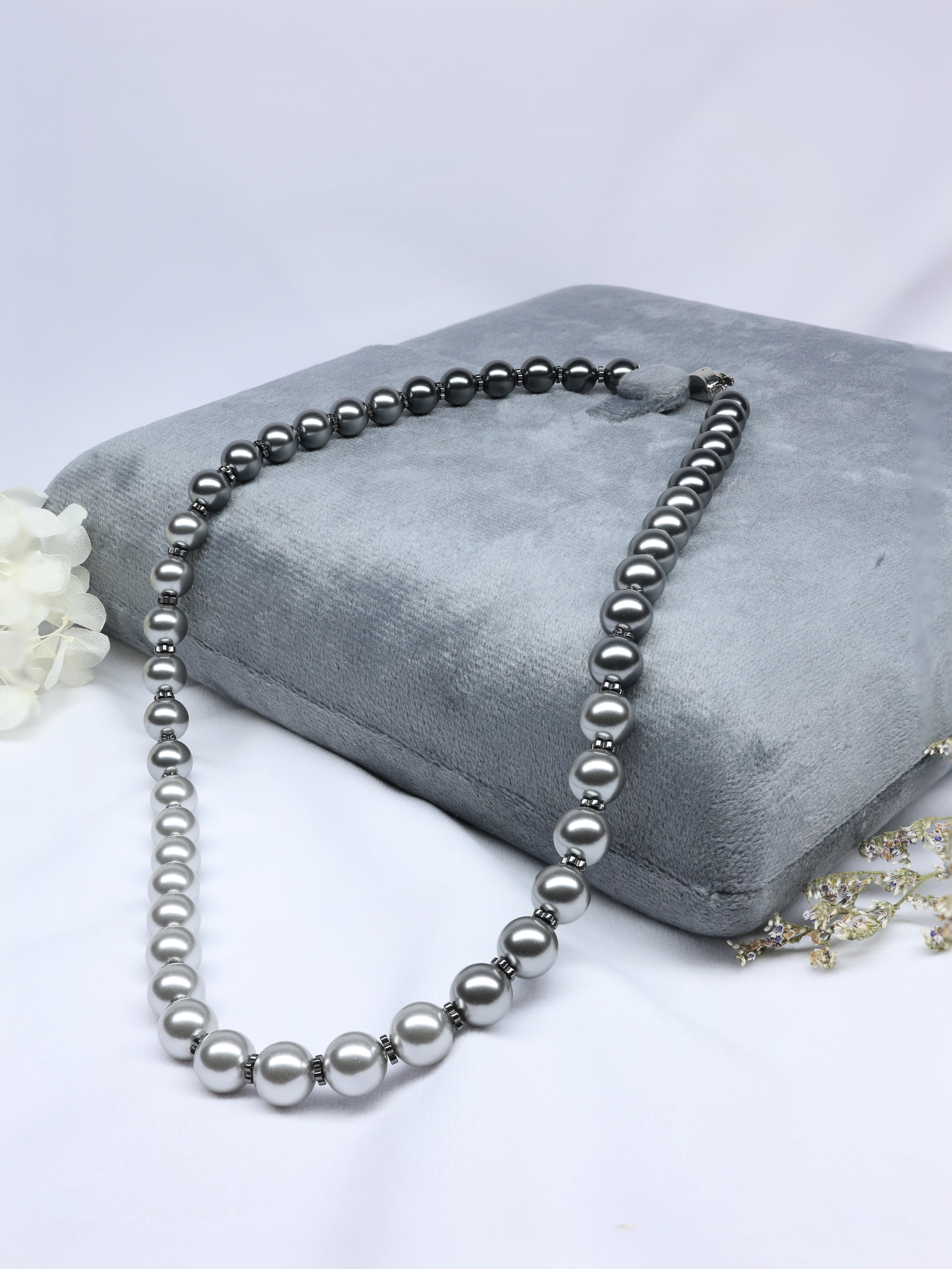 Black Pearl necklace on a gray cushion with a white background