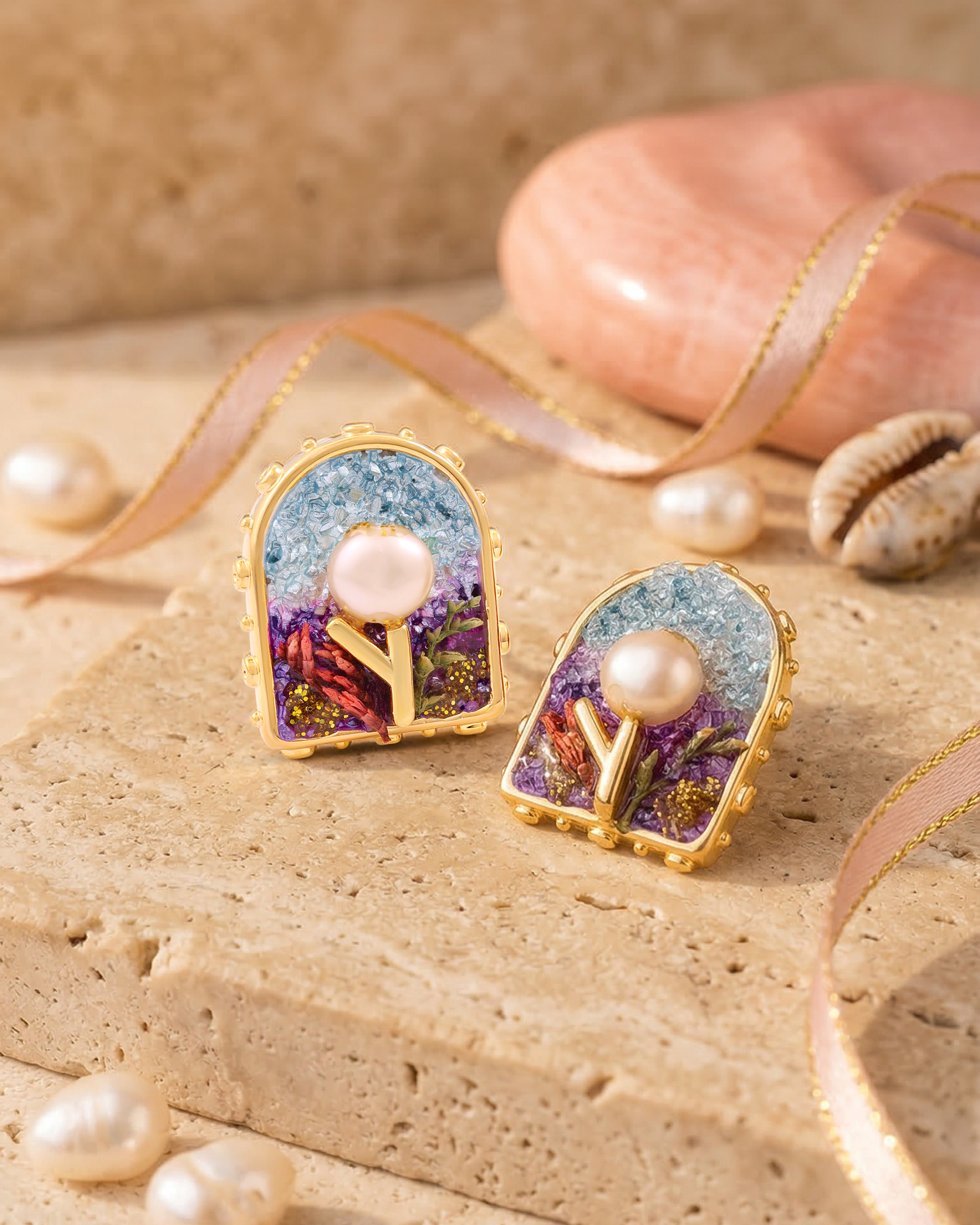 Decorative earrings with pearl-like stones on a beige surface
