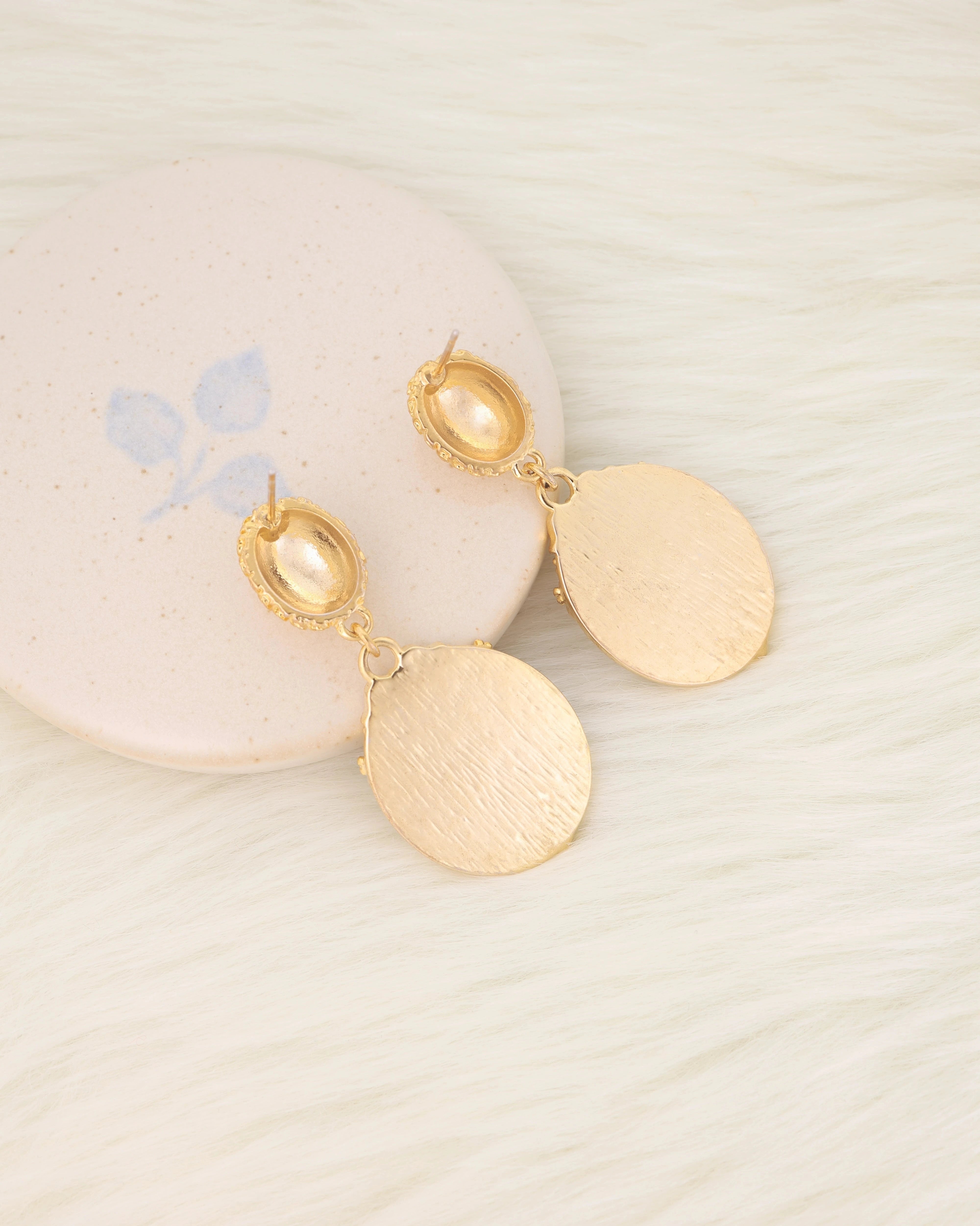 Gold earrings on a light background