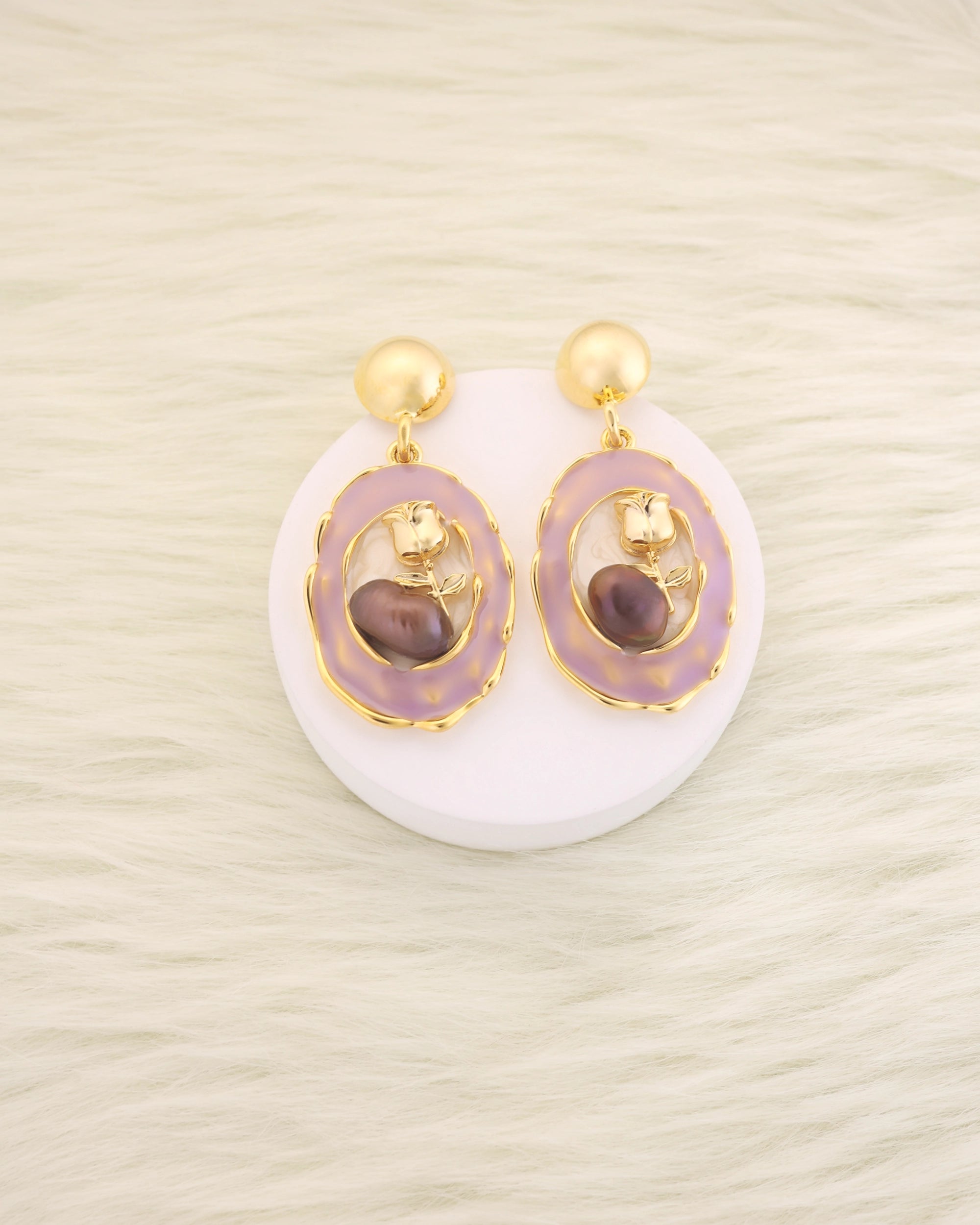 Pair of earrings with gold accents and purple stones on a white background