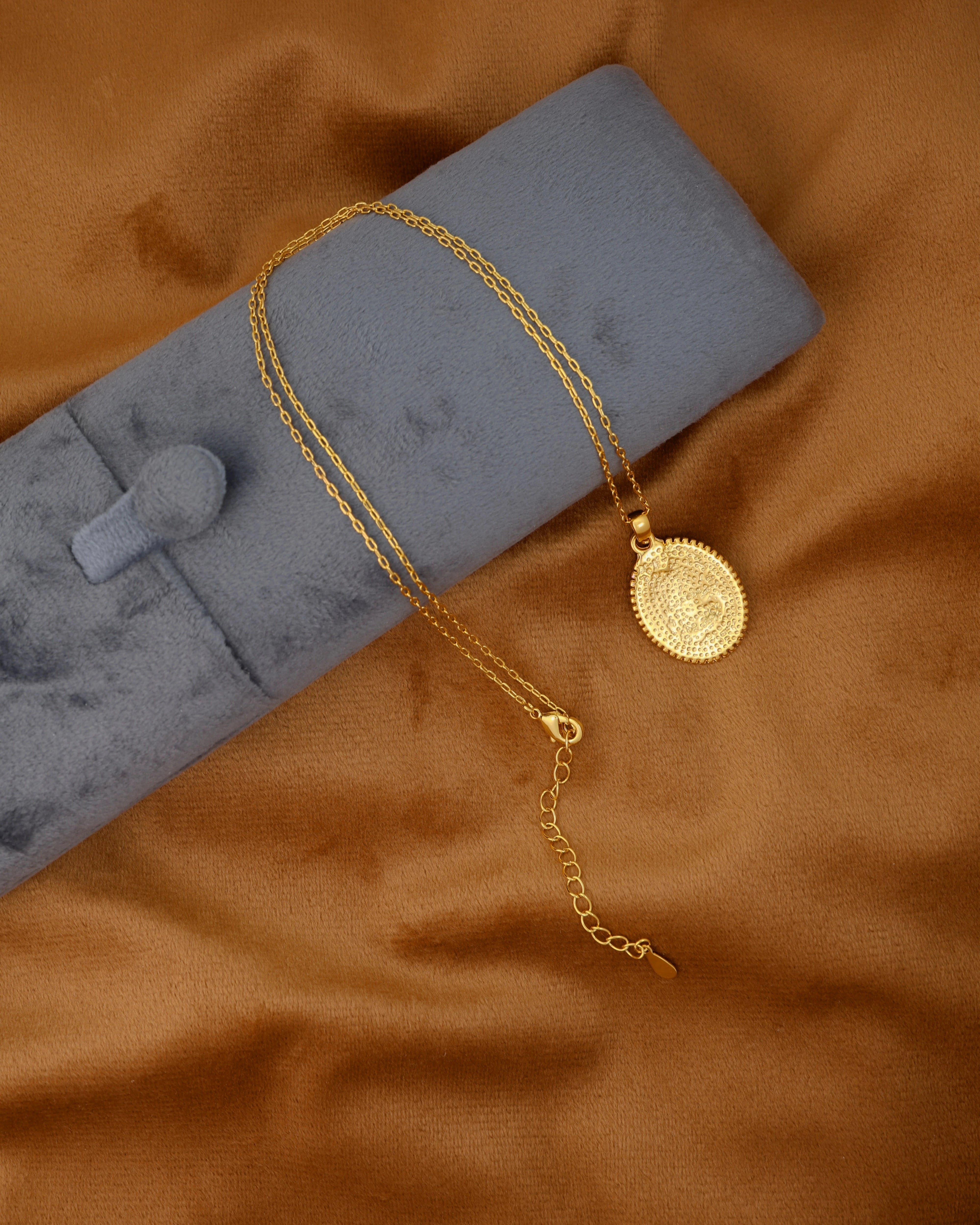 Gold necklace with a coin pendant on a brown fabric background