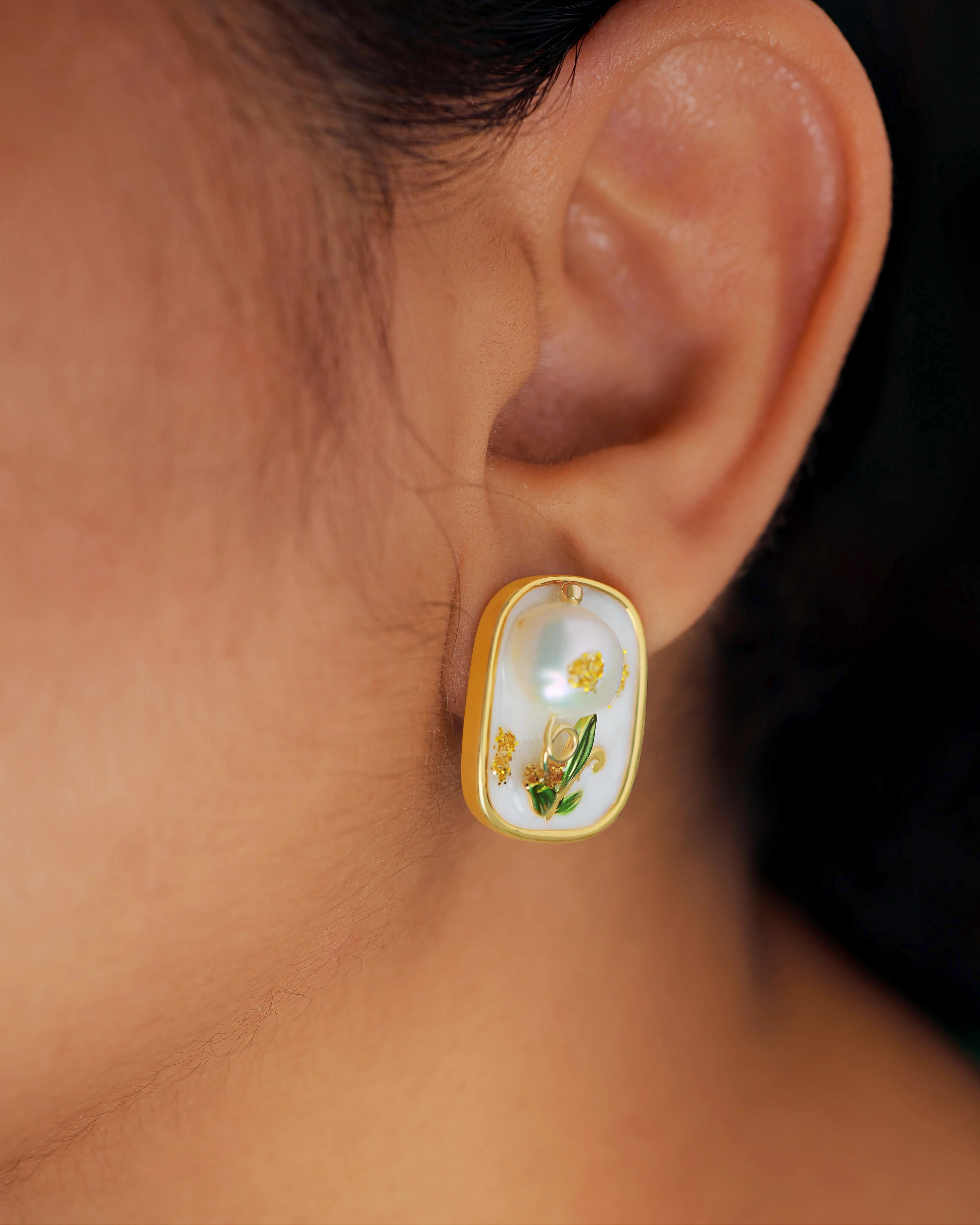 Close-up of an ear wearing a pearl earring with floral design