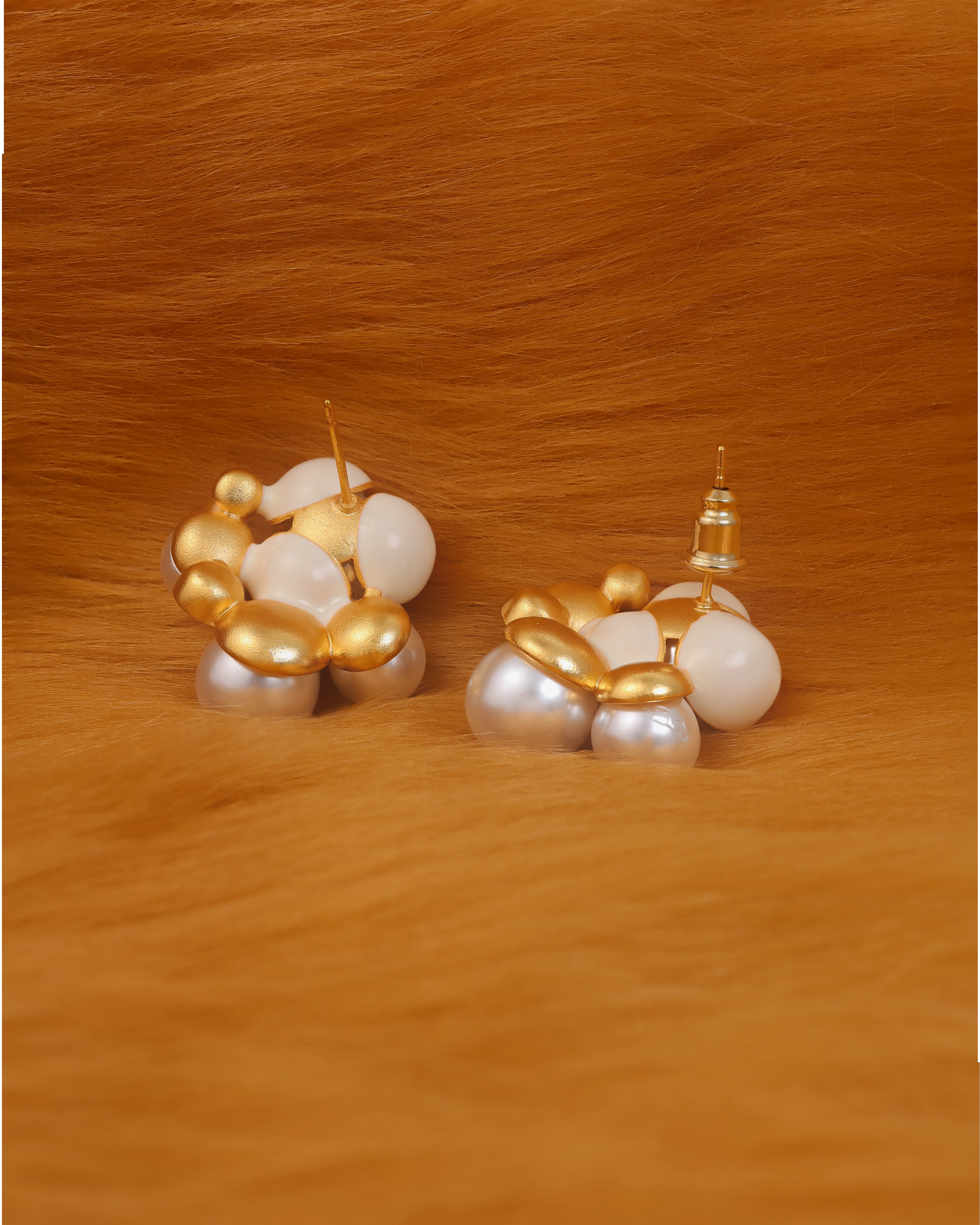 Large pearls studs with gold accents on a fur