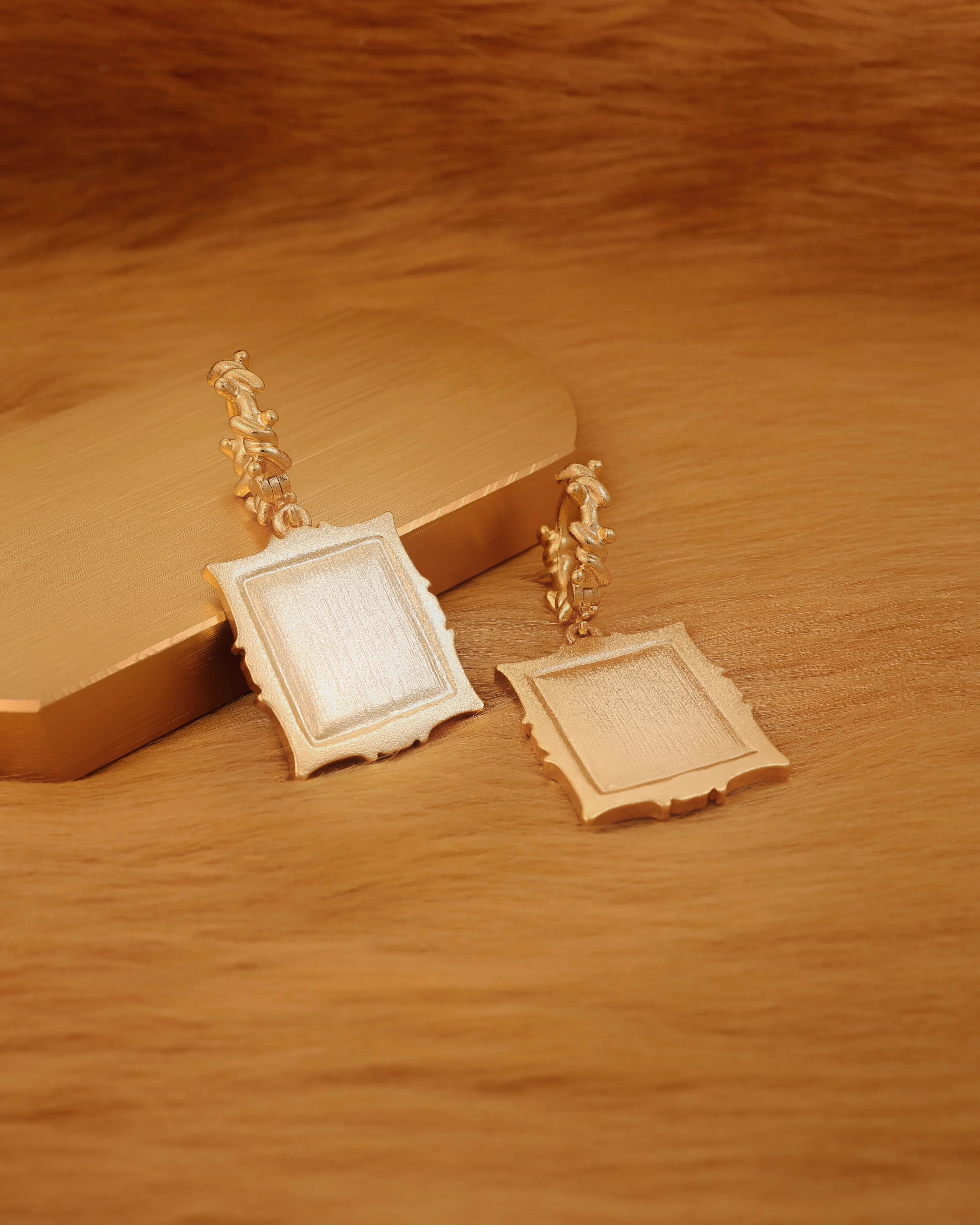 Pair of gold-framed earrings on a wooden surface