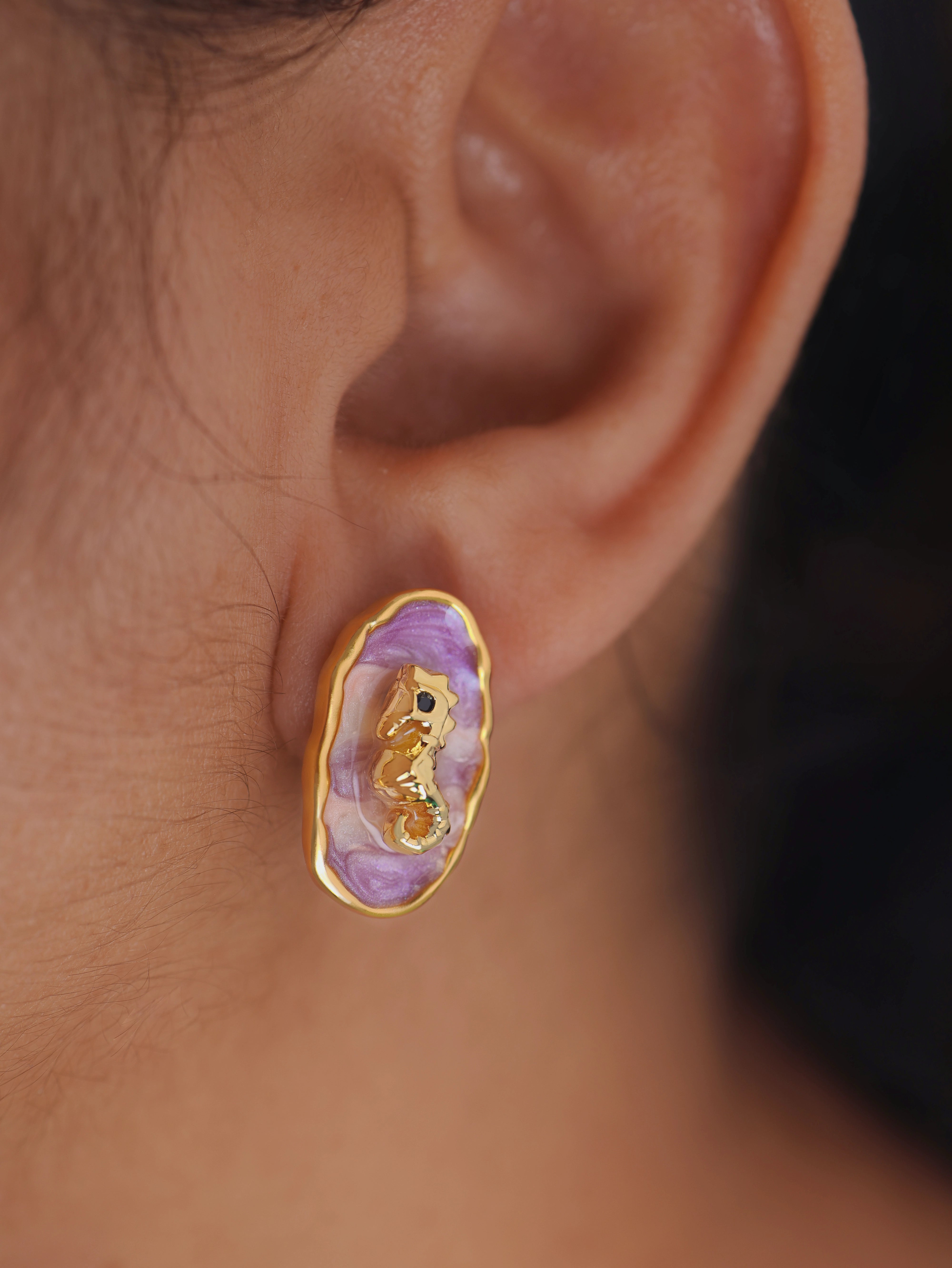 Close-up of an ear wearing a gold and purple earring.