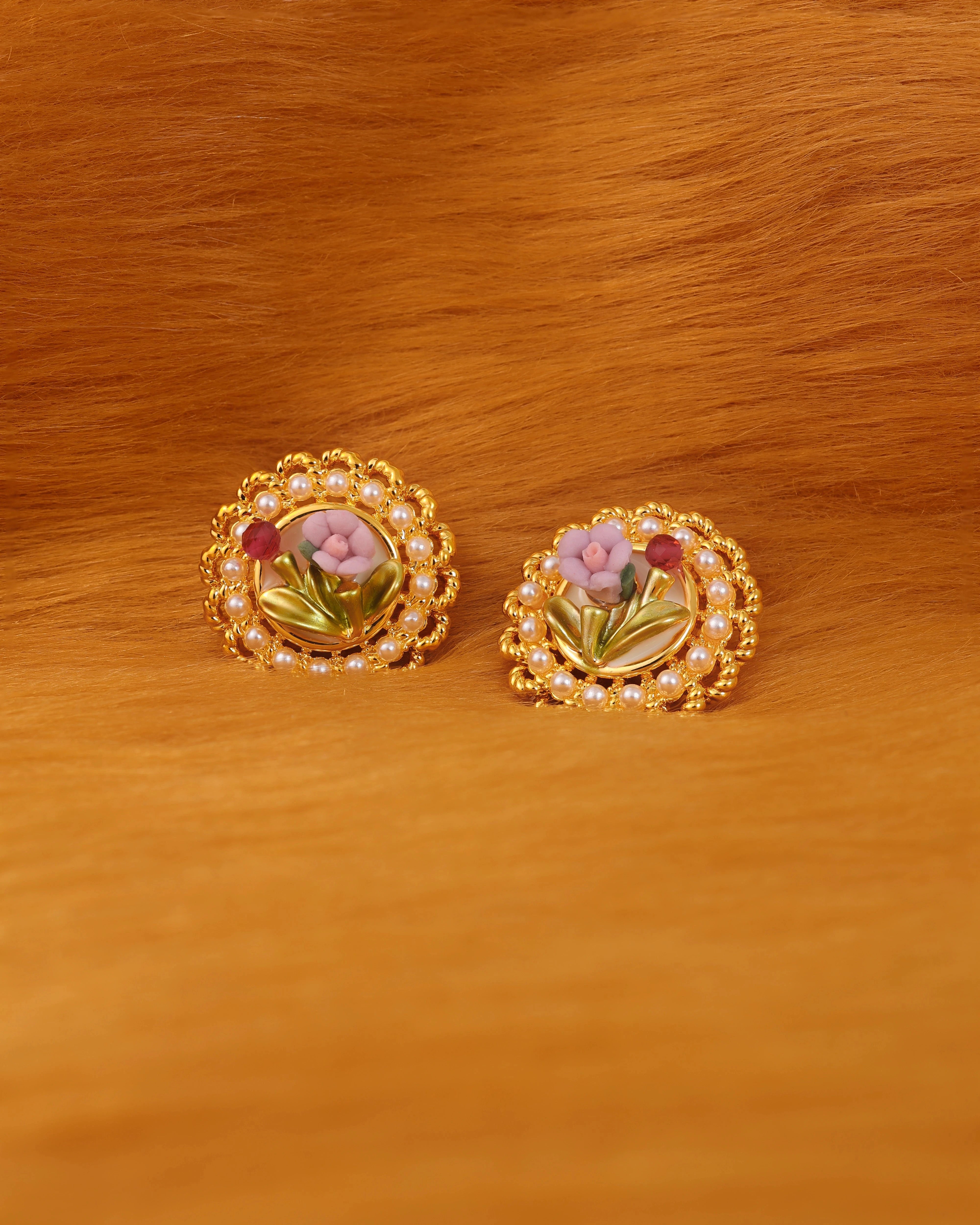 Pair of gold earrings with floral design on a golden fur