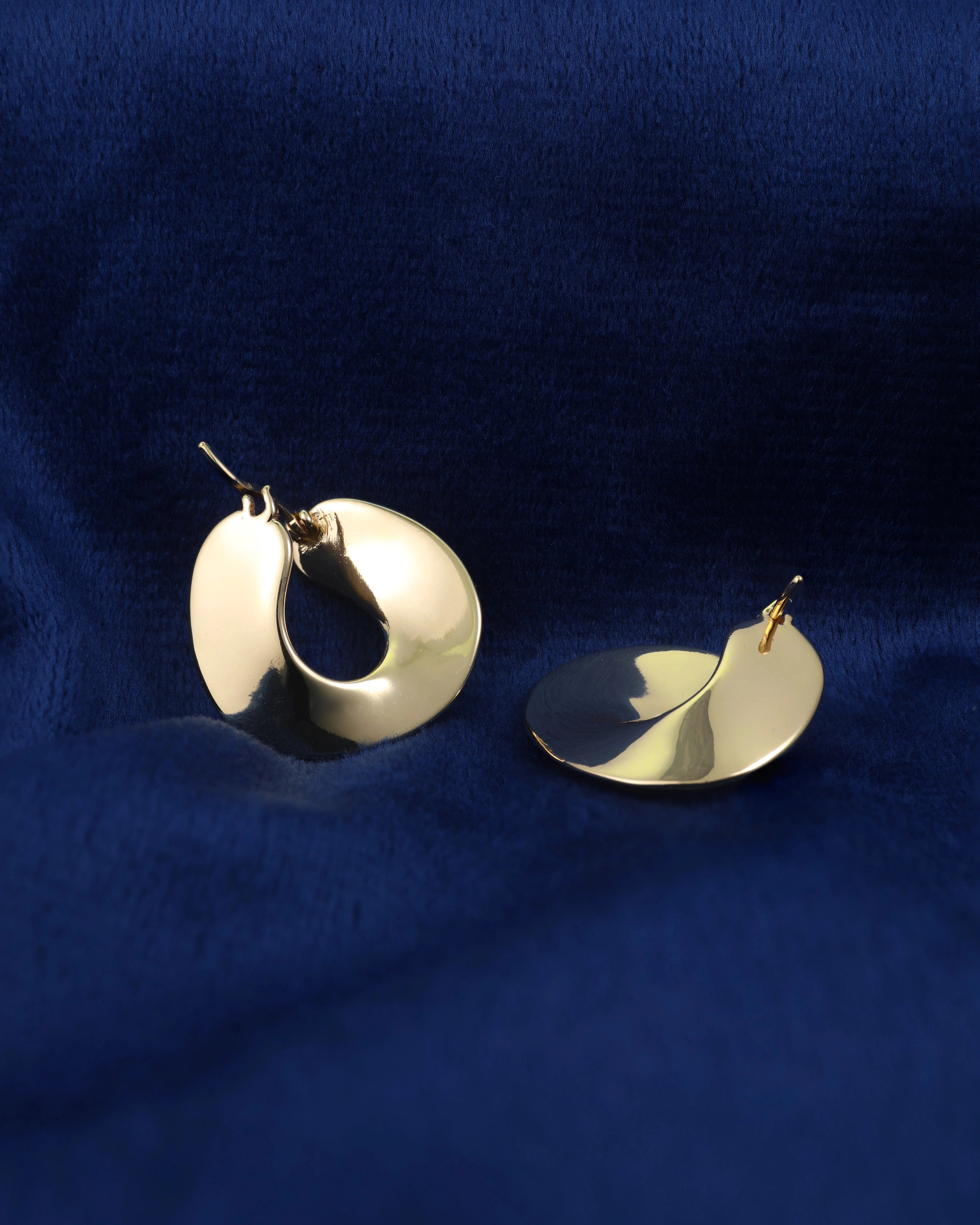 Gold hoop earrings on a blue fabric background