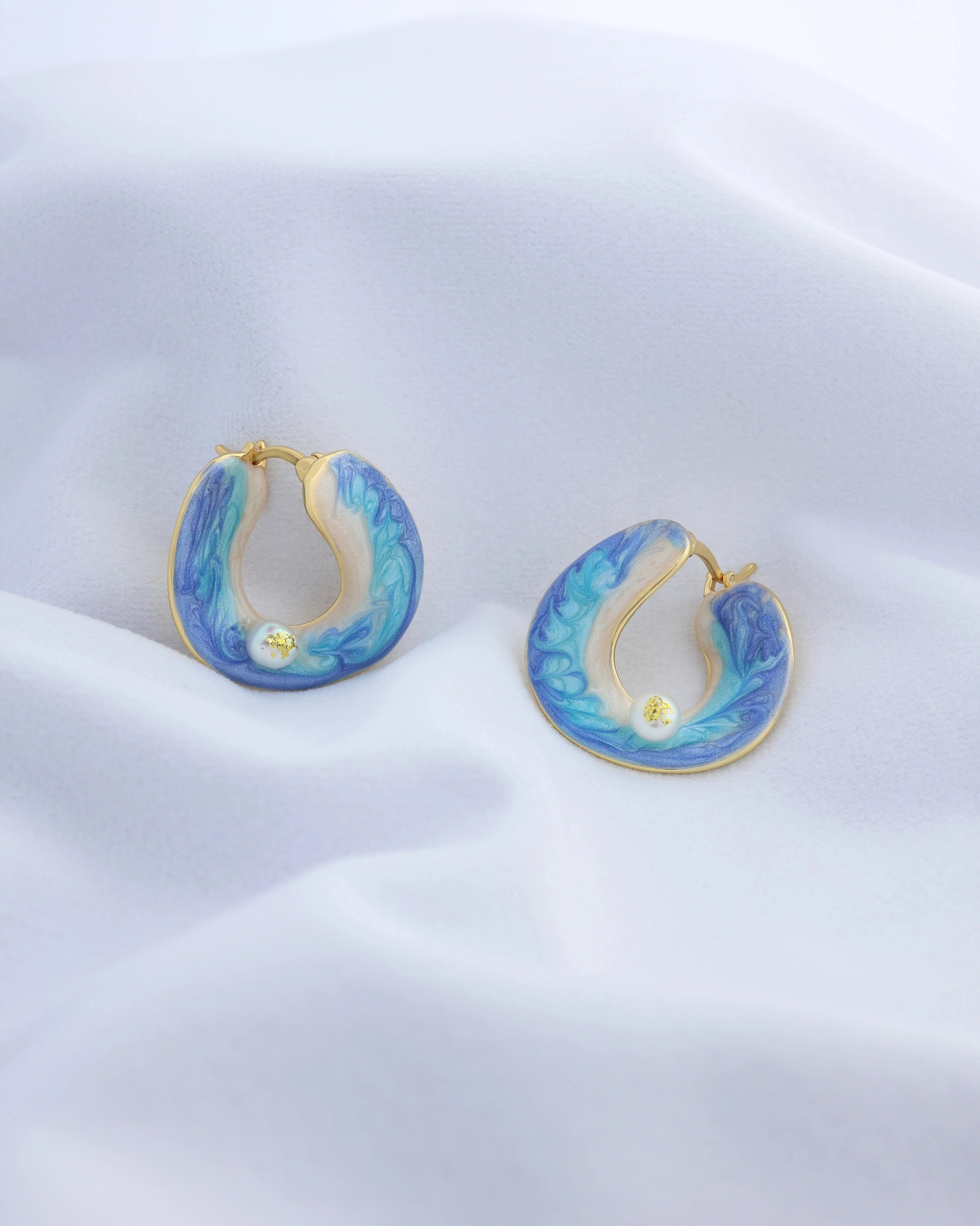 Blue hoop earrings with gold accents on a white background