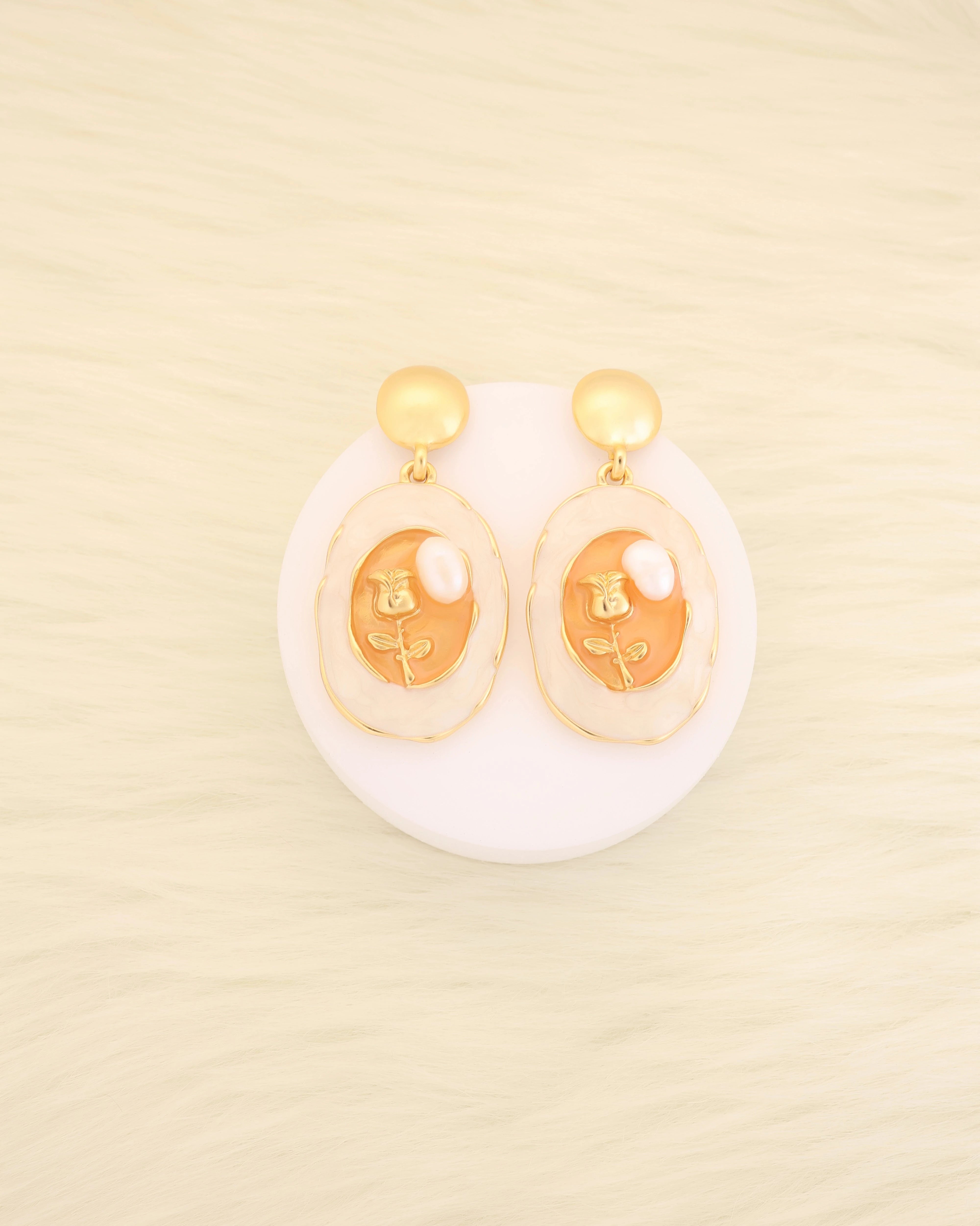 Pair of earrings with gold accents on a beige background