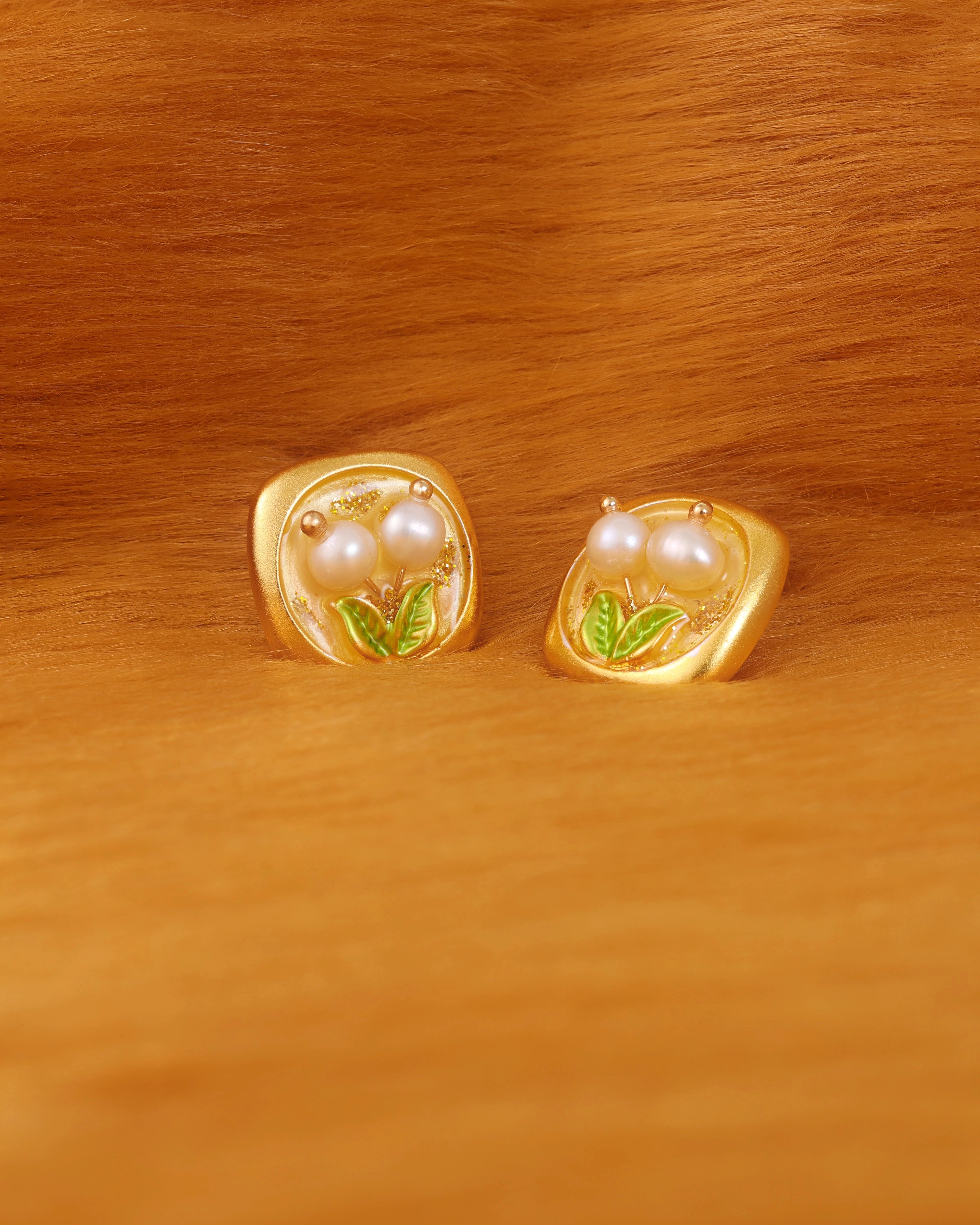 Gold earrings with pearl-like centers on a fur surface