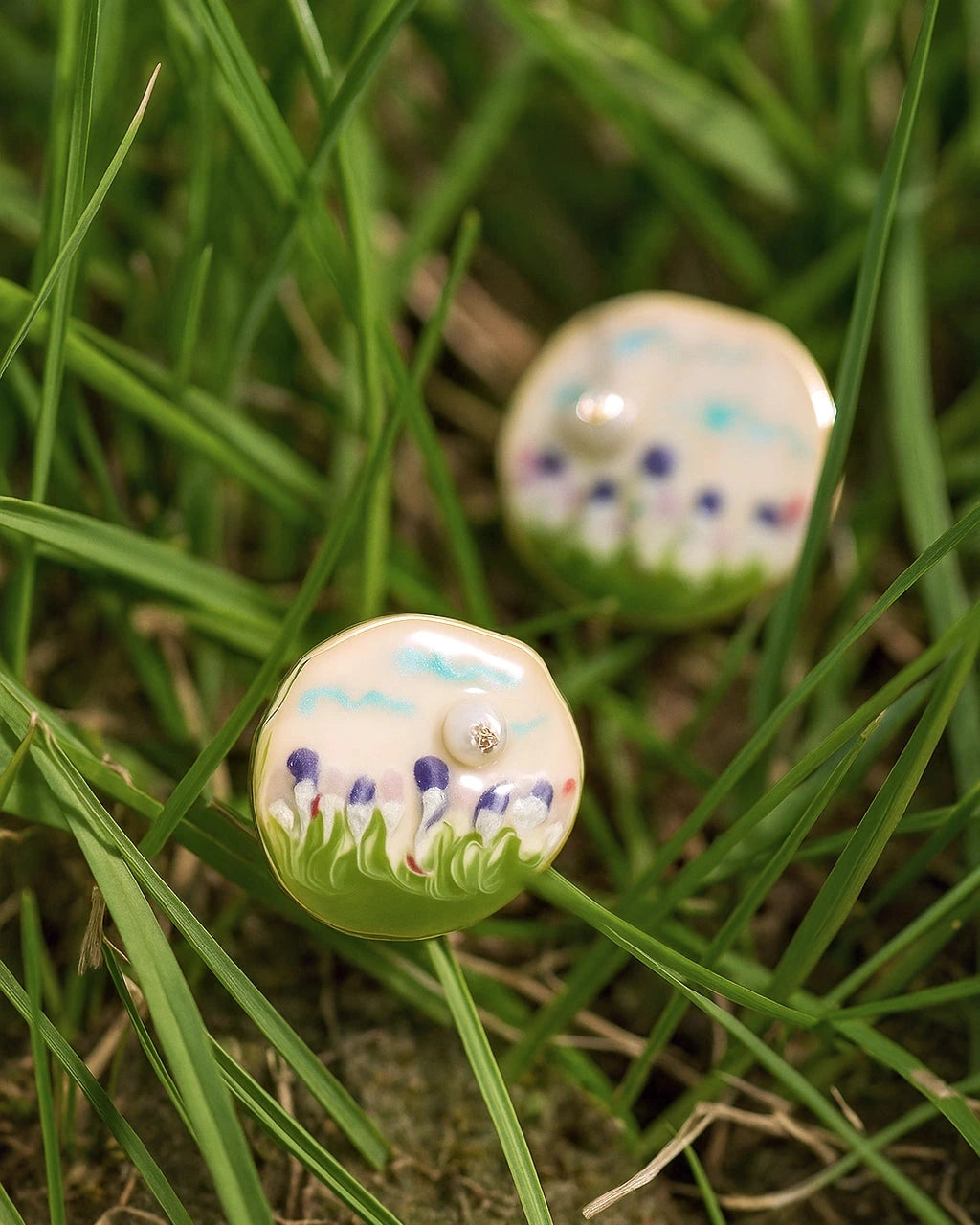 pearl ear studs with floral patterns on grass