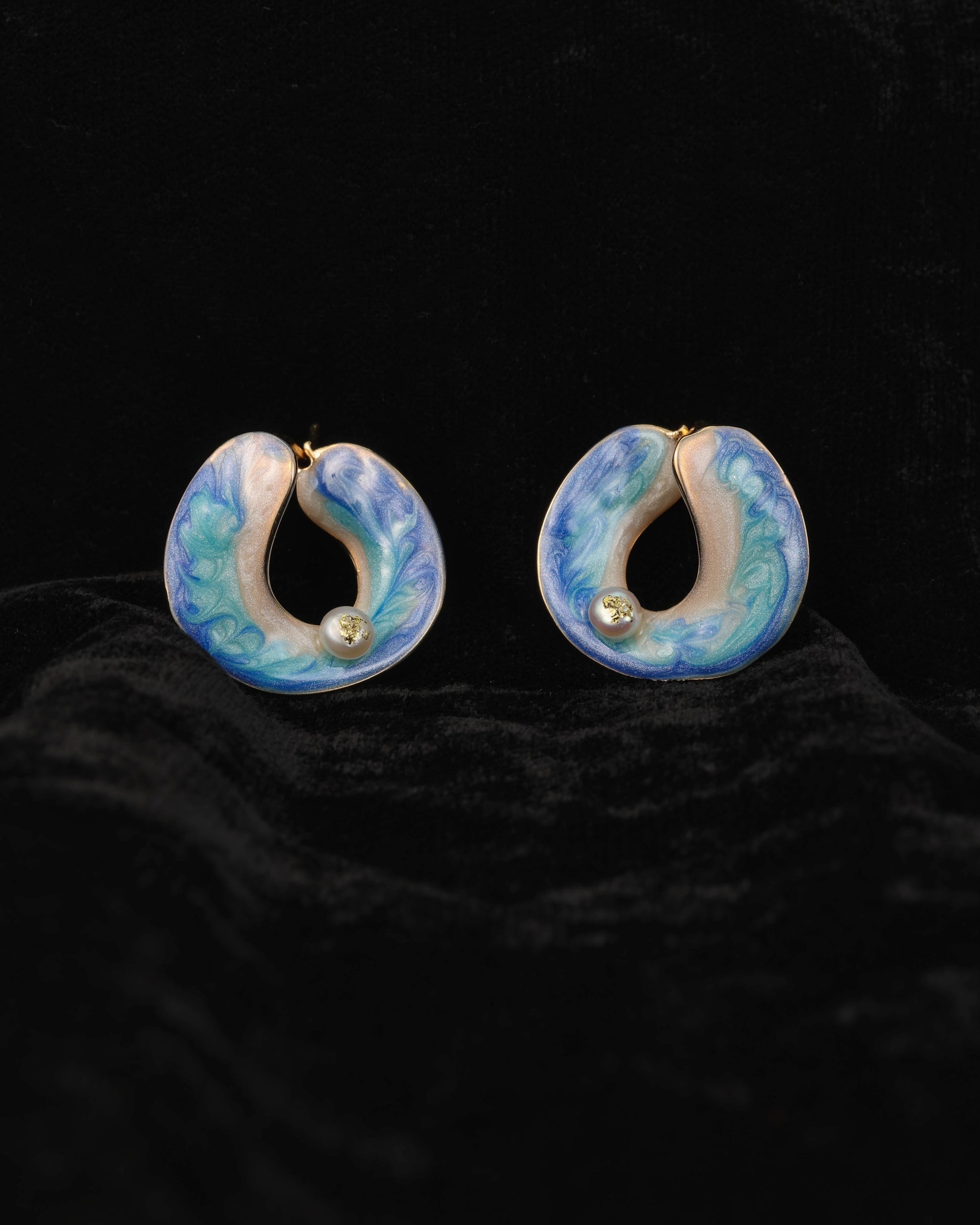 Pair of blue and white marbled hoop earrings on a dark background