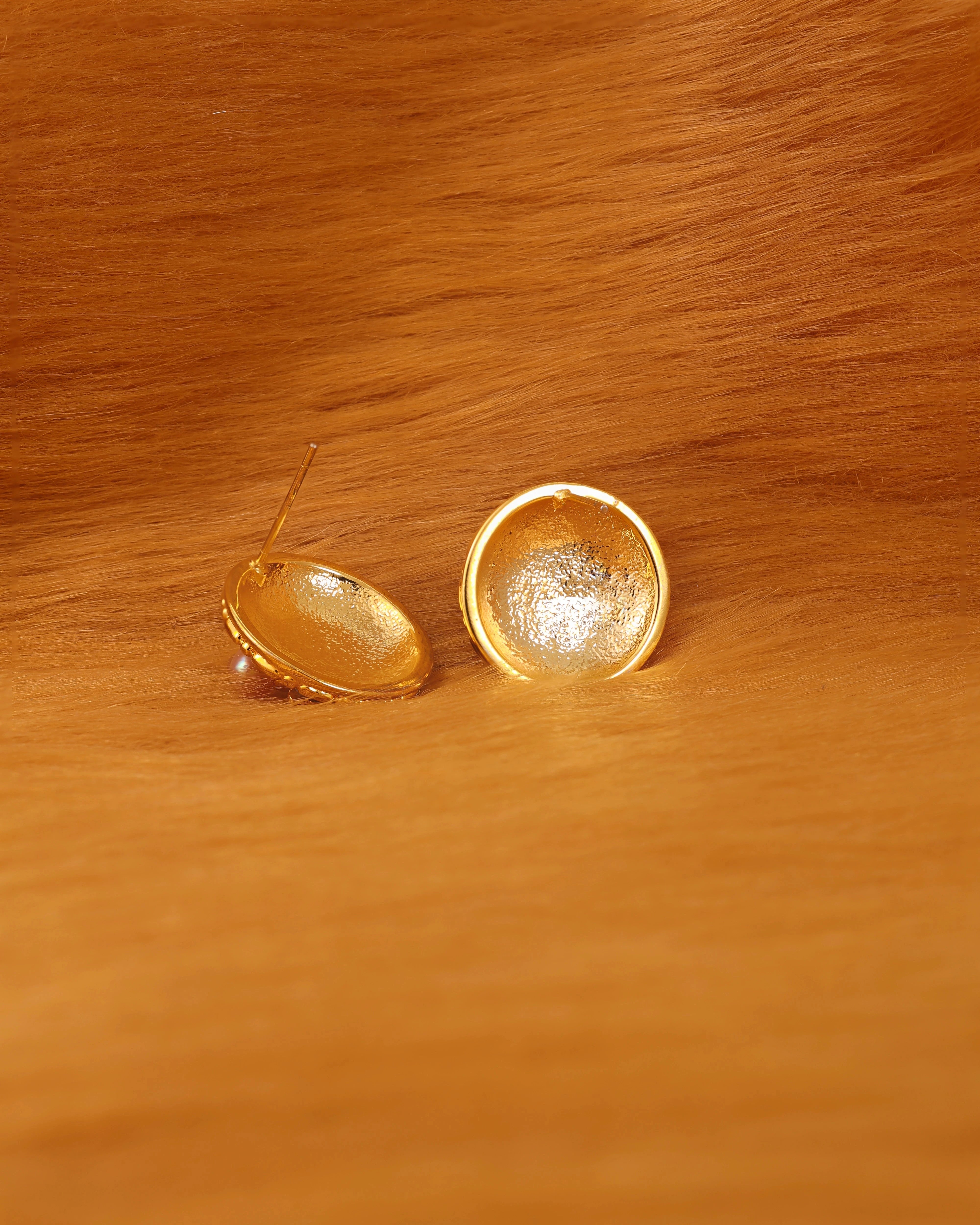 Gold earrings on a fur surface