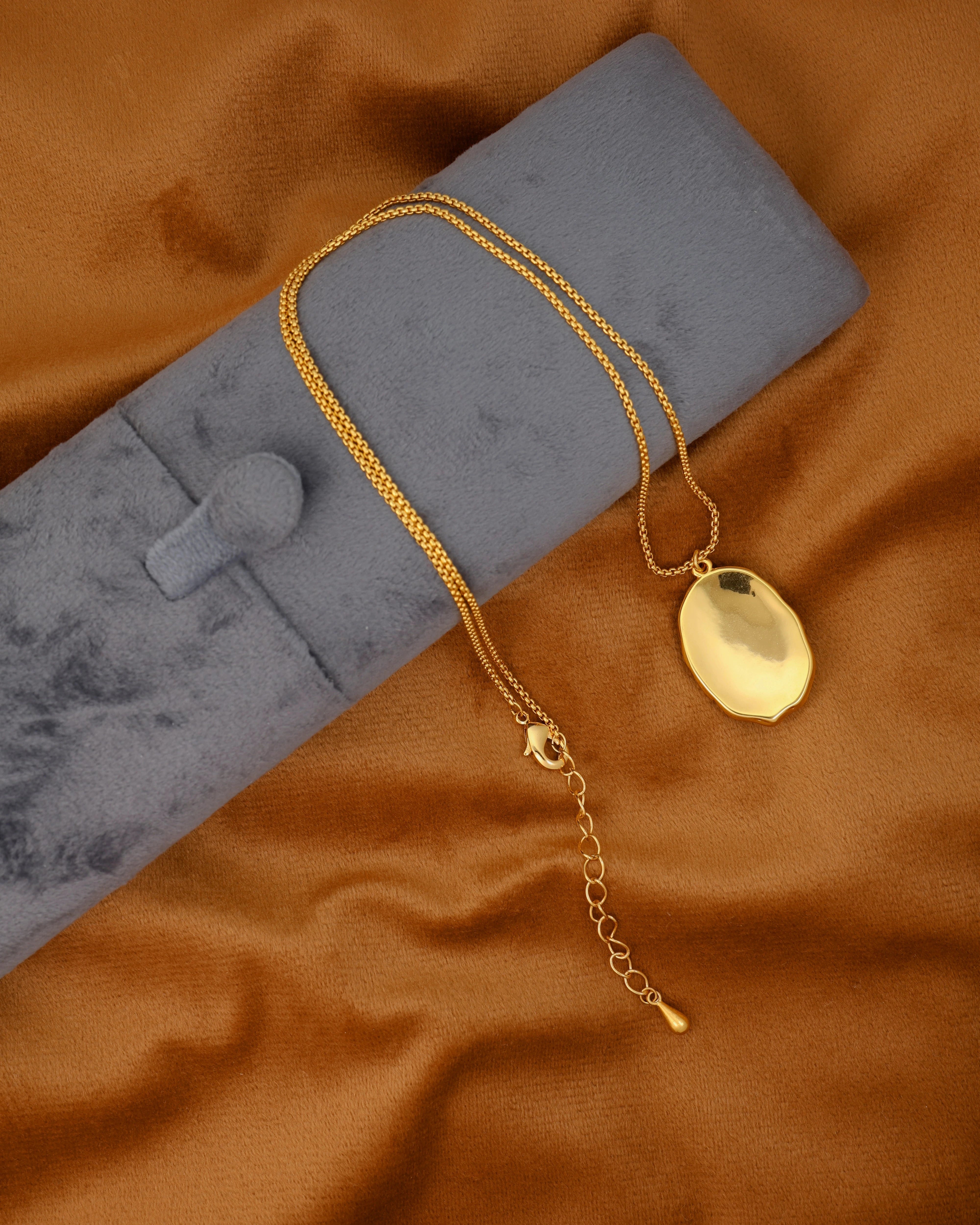 Gold necklace with a pendant on a brown fabric background