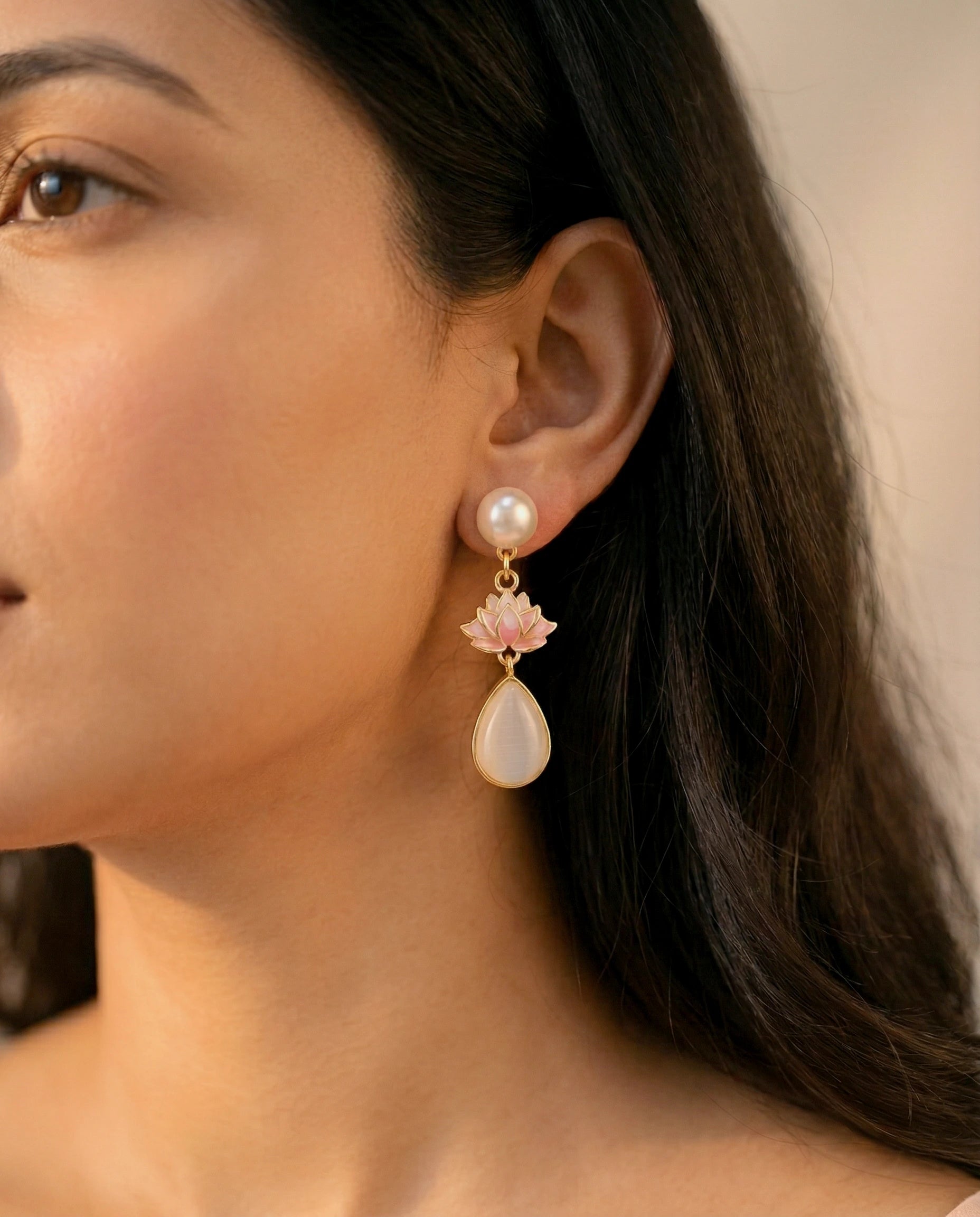 Close-up of a woman wearing a floral earring with a pearl drop.