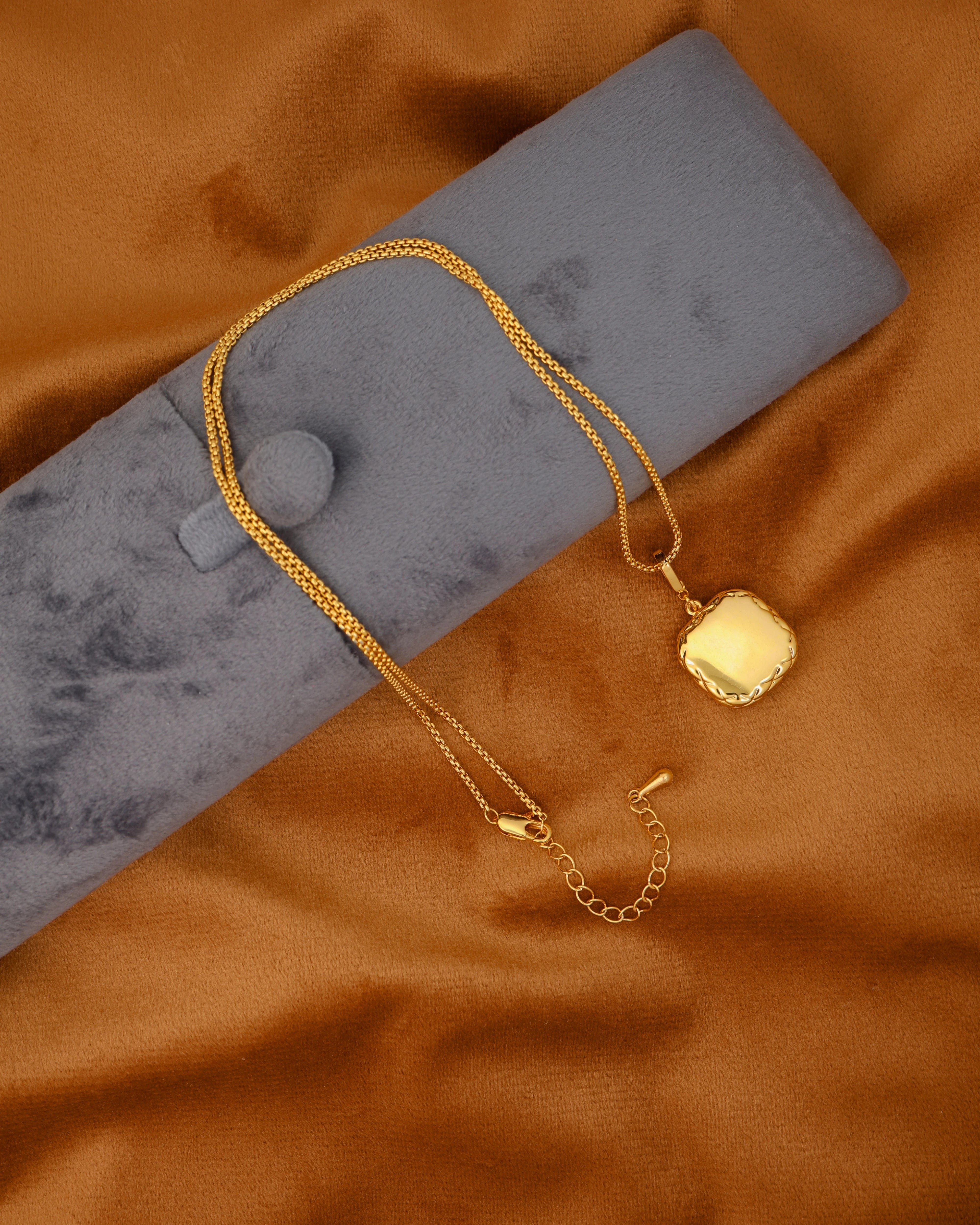 Gold necklace on a gray stand with a golden fabric background
