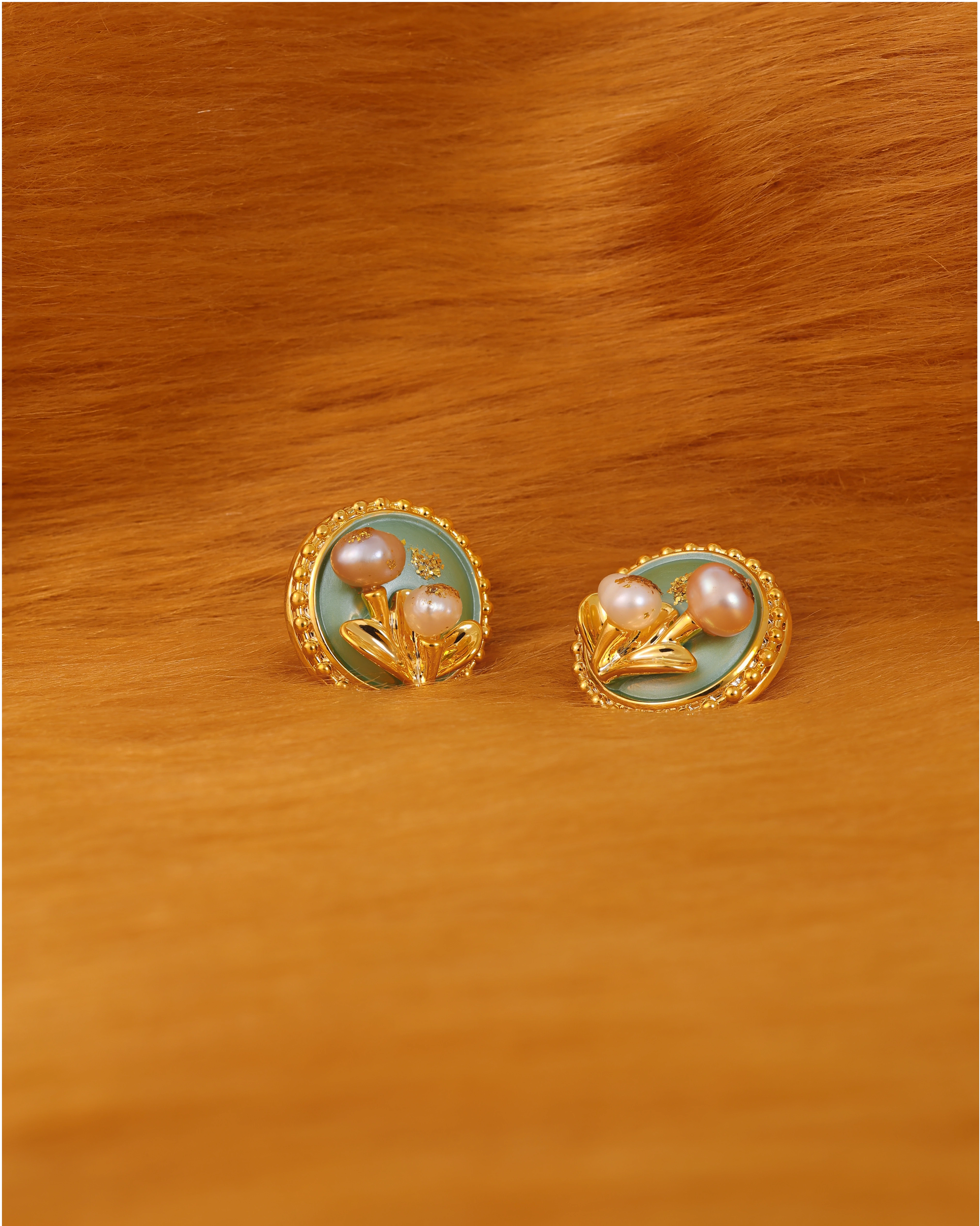 Pair of earrings with pearl-like stones on a fur surface