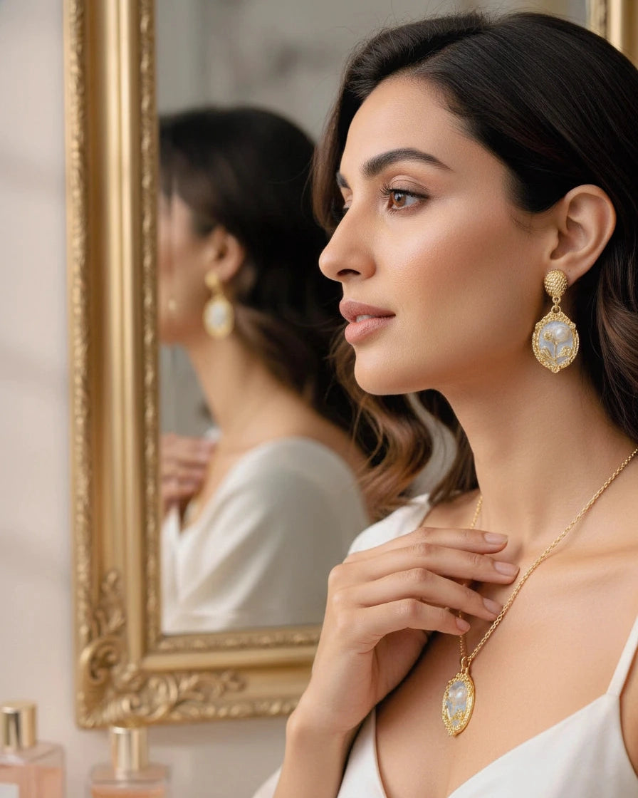 Woman wearing gold earrings and necklace in front of a mirror